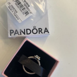 Pandora silverring med hjärta - Snygg silverring från Pandora med ett glittrande hjärta i centrum. Ringen har en detaljerad, pärlad ringband och en stor, klar sten formad som ett hjärta. 