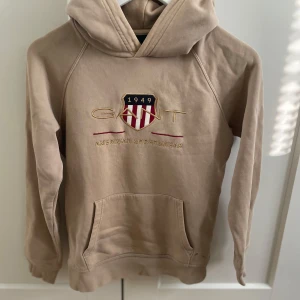 Beige hoodie från GANT  - Tja, säljer min beiga GANT hoodie. Den är i fint skick, men har använts flera gånger. Den är i storlek 146/152 och passar inte mig längre. Vid fler frågor är det bara att höra av sig. MVH Hugo