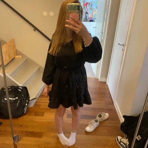 Svart kort klänning med volang - Säljer en svart kort klänning med volangkant nedtill och band i midjan. Den är ganska kort på mig som är 160.💕(köpare betalar frakten)