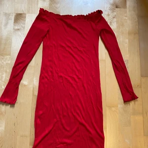 Röd offshoulder klänning från H&M - Snygg röd ribbad klänning från H&M Divided i storlek S. Offshoulder-modell med långa ärmar och volangkant upptill. Stretchigt material som sitter skönt och har en slim passform. Perfekt för dig som vill sticka ut med en enkel men trendig look.
