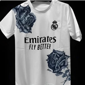 Real Madrid fotbollströja med rosor - Unik Real Madrid fotbollströja i polyester med stora ros-motiv på axel och nederkant. Finns i både vit och svart med klubbmärke och Emirates Fly Better-tryck på bröstet. Går att fixa eget nummer och namn det blir dock 85 kr dyrare