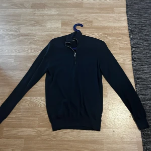 Svart merinoulltröja från Matinique - Säljer en marinblå långärmad tröja från Matinique i 100% merinoull. Tröjan har en hög krage med half zip-dragkedja och ribbade muddar. Perfekt för dig som gillar stilren och klassisk look med premiumkänsla. Ny pris 1300, använd 1 gång. Säljer då den blivit för liten.