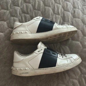Valentino Open sneakers i vitt och mörkblått  - Snygga Valentino Open sneakers i vitt skinn med bred svart rem över mitten. Skon är vit och mörkblå och säljs endast för 2399. pris kan diskuteras vi snabb affär 