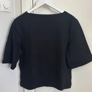 Svart topp från Gina Tricot - Enkel svart topp från Gina Tricot med båtkrage. Endast använd en gång!