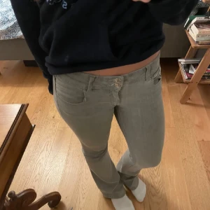 Grå bootcut jeans med låg midja - Säljer ett par grå jeans med snygg bootcut och låg midja. Jeansen har klassisk femficksdesign och stängs med dragkedja och knapp. 