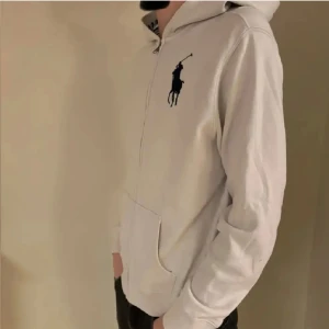 Vit hoodie från Polo Ralph Lauren  - Vit hoodie från Polo Ralph Lauren i storlek XL. Så passar SKlassisk design med dragkedja, huva och känguruficka. Stor svart logga på bröstet. Tillverkad i mjuk bomull, perfekt för chill dagar. Enkel och stilren look som funkar till det mesta. 439 för denna o 370 för de andra två 999 för alla tre