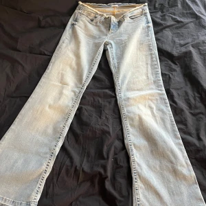 Ljusblå bootcut jeans med rå kant - Snygga ljusblå jeans med bootcut passform och rå, fransad midja. Klassisk femficksmodell i mjukt denimtyg, perfekt för en avslappnad och trendig look. Jeansen har normal passform och stängs med knapp och dragkedja. Med storlek 40 och har aldrig använt.