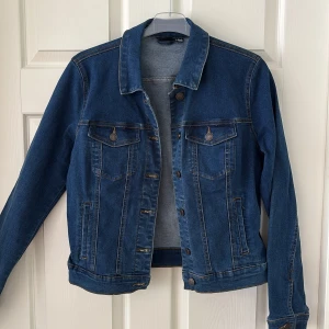 Blå jeansjacka - Snygg blå jeansjacka med klassisk passform och detaljerade sömmar. Jackan har två bröstfickor med knappar, sidofickor och knappar framtill. Perfekt att slänga över en hoodie eller t-shirt för en chill look.