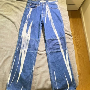 Our Legacy jeans 29 waist - Unika blå jeans från Our Legacy med raka ben och coolt vitt målat print längs hela byxorna. Klassisk femficksmodell i bomullsdenim med normal passform. Perfekta för dig som vill sticka ut med en kreativ och edgy look. Väldigt bra skick inga defekter alls och är knappt använda. Äkta såklart