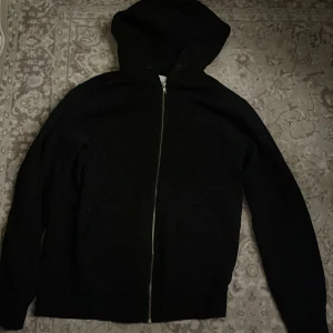 Svart hoodie från Jack & Jones  - Svart hoodie från Jack & Jones i storlek M. Klassisk modell med huva och hel dragkedja framtill. Tröjan har långa ärmar och är tillverkad i mjuk bomull, perfekt för chill dagar eller när du vill ha en enkel och clean look.