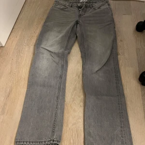 Grå jeans från 157 Icon - Säljer ett par grå jeans från 157 Icon med klassisk femficksdesign och raka ben. Jeansen har en snygg tvättad look och är tillverkade i bomull. Lite sönder vid ena bakfickan men det syns inte jätte mycket och går enkelt att laga
