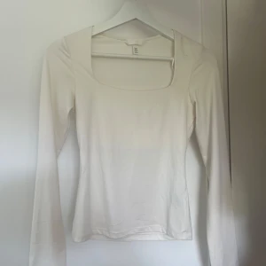 Vit långärmad topp från H&M XS - En vit långärmad topp från H&M i storlek XS. Toppen har en fyrkantig ringning och är figurnära i modellen. 