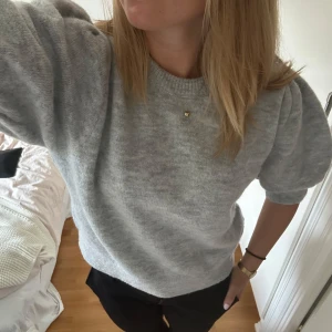 Grå stickad tröja med puffärm - Säljer en grå stickad tröja från Gina Tricot i storlek s, med puffiga korta ärmar och rund hals. Knappt använd  sen jag köpte den så i väldigt bra skick. 