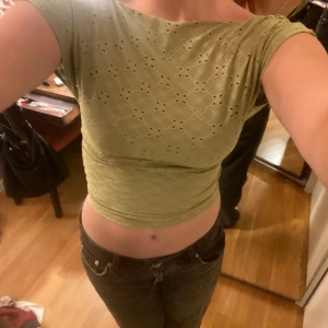 Ljusgrön croppad topp med öppen rygg - Säljer en ljusgrön croppad topp med korta ärmar och snyggt hålmönster över hela tyget + öppen rygg!