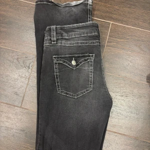 Svarta bootcut jeans Gina Tricot - Snygga svarta bootcut jeans från Gina Tricot med markerade vita sömmar och klassiska fickor bak. Jeansen har en lätt tvättad look och är tillverkade i mjukt bomullsmaterial med stretch. Perfekta för dig som gillar en trendig och bekväm stil.