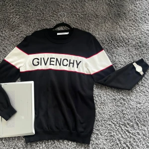 Givenchy tröja  - Snygg svart tröja från Givenchy med vit panel och röda detaljer över bröstet och ärmarna. Stor Givenchy-logga framtill. Långärmad och rund halsringning, tillverkad i mjukt material som känns lyxigt och bekvämt.