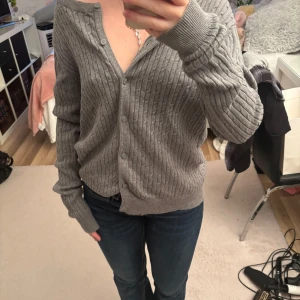 Grå ribbad kofta med knappar - Mysig grå kofta med ribbat mönster och knappar framtill. Använd fåtal gånger. I storlek M, men passar "oversized" på mig som i vanliga fall bär XS/S.