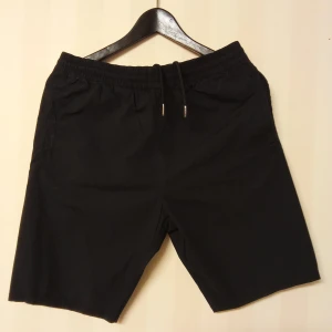 Svarta bomullsshorts från Emilio XS - Svarta shorts från Emilio i 100% bomull med elastisk midja och snörning. Klassisk rak modell med fickor på sidorna, perfekta för sommardagar. Snygg och enkel design som funkar till det mesta.                                                Kan skickas med extra pris via post.