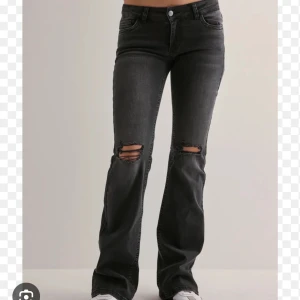 Svarta lågmidjade bootcut jeans från Nelly - Snygga svarta lågmidjade bootcut jeans från Nelly med låg midja och slitna detaljer över knäna. Endast testade, har ej kommit till användning lappen sitter kvar. Jeansen har coola bakfickor med zigzag-söm och är gjorda i stretchig denim för en bekväm passform. Köpta för 700 kr💞