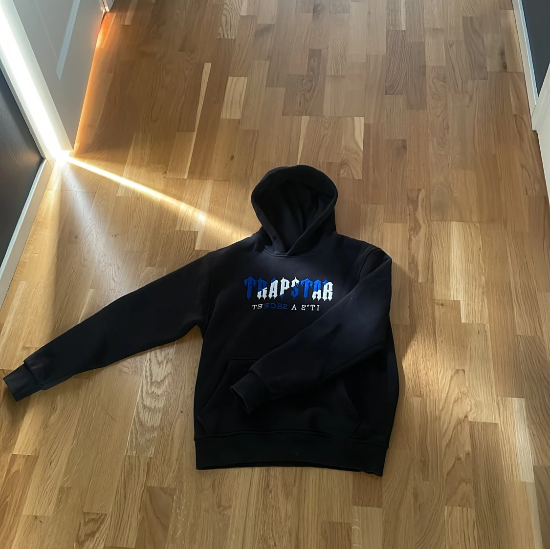 Svart Trapstar hoodie med blå/vit text