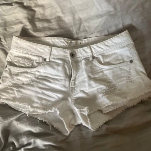 Vita jeansshorts från Lindex, strl 38 - Snygga vita jeansshorts från Lindex med fransig kant och slitna detaljer framtill. Klassisk med kna. 
