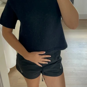 Mörkblå stickad kortärmad tröja - Kortärmad stickad tröja från Gina Tricot i mörkblå färg. Tröjan har en rak, boxig passform och ribbade kanter vid halsringning, ärmslut och nederkant. Perfekt att styla med jeans.