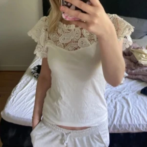 Vit blus med spetsdetaljer - Supersöt vit blus med breda spetsärmar och vackert mönstrad spets upptill. Blusen har rund halsringning och är figurnära i modellen. Perfekt för dig som gillar romantiska och feminina detaljer. Köpte toppen i Spanien använt 2-3 ggr