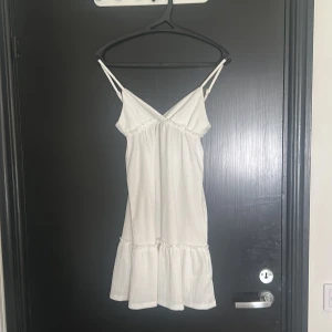 Vit sommarklänning - Supersöt vit kortklänning från DIVIDED med tunna axelband och v-ringning. Klänningen har en volang nertill. Denna klänningen var en stor favorit förra sommaren!!