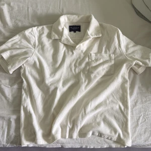 Vit frottéskjorta från Bondelid - Vit kortärmad skjorta från Bondelid i mjuk frotté. Skjortan har klassisk krage, bröstficka och relaxed fit. Perfekt för chill dagar eller strandhäng. Enkel och stilren design som är lätt att matcha. Storlek S men passar mer som XS