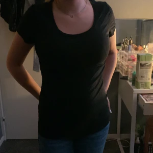 Svart t-shirt från Lindex - En basic svart t-shirt från Lindex med rund halsringning och korta ärmar. Modellen är figurnära och passar perfekt till jeans eller kjol. Tillverkad i mjuk bomull som känns skön mot huden.