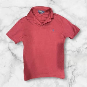 Röd pikétröja från Polo Ralph Lauren - Klassisk röd pikétröja från Polo Ralph Lauren i bomull med blå broderad logga på bröstet. Tröjan har korta ärmar, krage och knappslå. Slim fit-modell som ger en snygg och stilren look. Skriv gärna vid frågor Lorenzo&Co ✍️