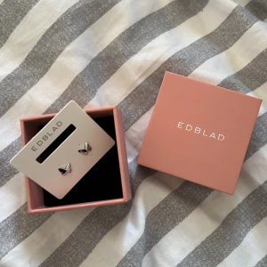 Fjärilsörhängen i silver från Edblad - Supersöta små örhängen från Edblad i form av fjärilar. De är i blankt silverfärgat material och har en stilren och minimalistisk design som passar perfekt till din vardagsstil. Kommer i original ask, perfekt som present eller till dig själv.