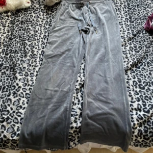 Gråa vida mjukisbyxor med snörning - Mysiga grå mjukisbyxor i ett mjukt och glansigt material med breda ben och dragsko i midjan. Perfekta för chill dagar hemma eller när du vill vara bekväm men ändå se snygg ut. Snygg loose fit och klassisk look.
