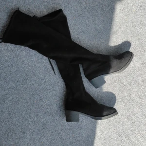 Svarta knä stövlar i mocka - Snygga svarta knee high stövlar med låg klack och rund tå. Gjorda i mjuk mocka med snörning upptill för perfekt passform. Perfekta till höst- och vinterlooken och funkar lika bra till kjol som till jeans. Används några gånger, lite sletning vid knytningen 
