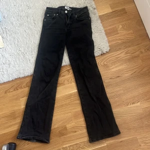 Svarta jeans från lager 157 - Svarta jeans från lager 157 med klassisk femficksdesign och raka ben. Jeansen har snygga detaljer som silverfärgade knappar och bakfickor med lock. Perfekta för dig som gillar en stilren look med lite edge.