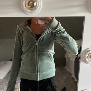 Grön velour hoodiejacka med dragkedja - Mjuk och skön ljusgrön hoodiejacka  med dragkedja framtill och fickor. Jackan har huva och ribbade muddar vid ärmslut och nederkant. Perfekt för en chill och avslappnad stil.