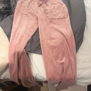 Rosa velourbyxor Juicy Couture S - Mysiga rosa mjukisbyxor från Juicy Couture i velour med dragsko i midjan och stora fickor framtill. Perfekta för chill dagar och har den klassiska Juicy-looken. Snygg loose passform och supermjukt material.☺️