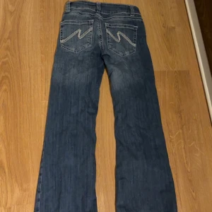 Low Waist Bootcut Stitch Jeans   - Blåa low waist bootcut jeans från Nelly, de är i storlek 32. Det är i fint och bra skick och ej använda så ofta då de var långa på mig som är 153. De har därav fått ett hål men de synns ej när man har de på sig. 