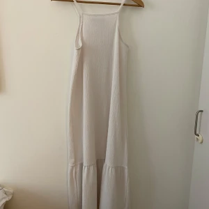 Vit långklänning från Lager 157 - Luftig och stilren vit långklänning från Lager 157 med tunna axelband och lätt rynkad nederdel💕 har även en volang nere vid klänningen. Använd och tvättad🫶🏼