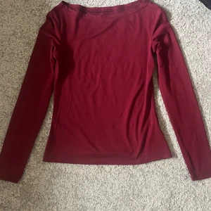 Vinröd långärmad topp i bomull - En enkel och stilren vinröd långärmad topp i mjuk bomull. Modellen är figurnära med rund halsringning och passar perfekt till jeans eller kjol. Snygg att bära både till skolan och på stan.