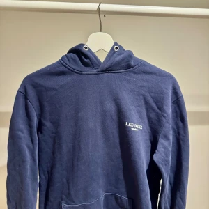 Mörkblå hoodie från Les Deux - Snygg mörkblå hoodie från Les Deux med liten vit logga på bröstet.