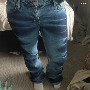 Blå raka jeans med vintagekänsla - Säljer ett par blå jeans med rak passform och klassisk femficksdesign. Jeansen har en snygg tvättad look och normal midja. Perfekta för dig som gillar en avslappnad och tidlös stil. Materialet är robust denim som håller länge. Det är lite slitna i ändarna(kom privat för bilder på defekterna)