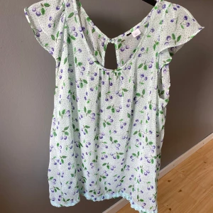 Ljusblå blus - Säljer en ljusblå blus med lila körsbär på. Bara använt några få gånger