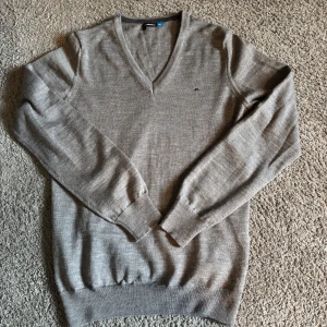 J.Lindeberg tröja i merinoull  - Snygg grå v-ringad tröja från J.Lindeberg i 100% merinoull. Använd en gång, så den är i nyskick och har inga defekter. Nypris 1300kr. Skriv vid frågor!😃
