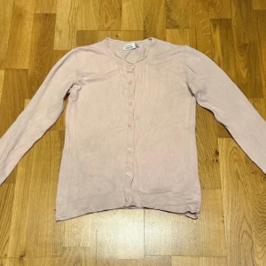 Ljusrosa kofta  - Säljer en söt ljusrosa kofta från Wera med långa ärmar och knappar hela vägen framtill. Koftan är tunn och mjuk, perfekt att slänga över en topp. Enkel och stilren design som funkar till många outfits. Den har använts ett par gånger men är ändå i fint skick.