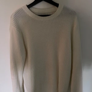 Beige stickad tröja med rund hals - En stilren beige stickad tröja med rund halsringning och långärmad modell. Tröjan har en grovstickad struktur som ger en avslappnad och trendig look. Perfekt att matcha med jeans eller kjol för en enkel men snygg outfit.