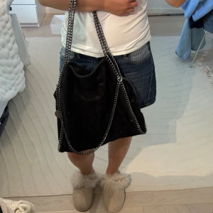 Axelväska - Stella liknande väska i en svart/skimrande färg. Väskan kan bäras på två olika sätt och är väldigt rymlig, fungerar perfekt som skolväska!💓 har två olika fack. Inga skador eller defekter!