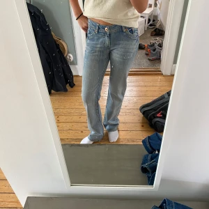 Ljusblå bootcut jeans - Säljer ett par bootcut jeans.Jeansen har fem fickor, knappgylf och snyggt slitna detaljer. Perfekta för dig som gillar en avslappnad och tidlös look.