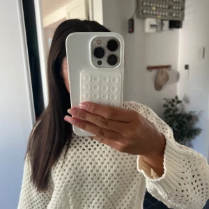 Vit stickad tröja med hålmönster - Säljer en vit stickad tröja med hålmönster och breda muddar vid ärmsluten. Tröjan har en loose passform och är långärmad, perfekt att slänga på sig över ett linne eller t-shirt. Enkel att styla med jeans för en chill look.