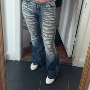 Jaded london jeans los waist - Säljer mina favorit jeans då jag inte får användning av dom längre, det är ett par blå low rise jeans från jaded London med bootcut passform. Jeansen har extremt slitna detaljer framtill, fransad midja och en cool, nästan zebra-liknande effekt. Materialet är klassisk denim och de har en riktigt edgy vibe. 